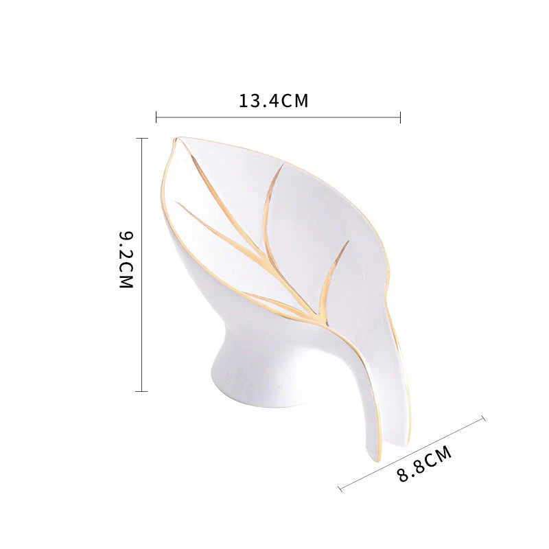 A ceramic soap dish with a sleek leaf-shaped design, featuring a suction cup base for secure and tidy placement in the bathroom or kitchen.