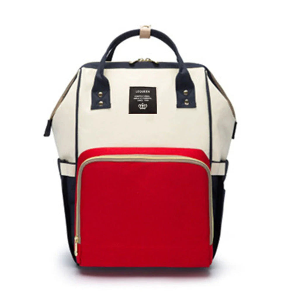 Stylish maternity diaper bag in various colors, featuring a paper bag design, separate bottle compartment, and discreet breastfeeding button.