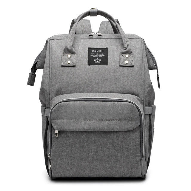 Stylish maternity diaper bag in various colors, featuring a paper bag design, separate bottle compartment, and discreet breastfeeding button.