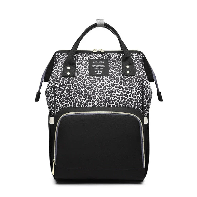 Stylish maternity diaper bag in various colors, featuring a paper bag design, separate bottle compartment, and discreet breastfeeding button.