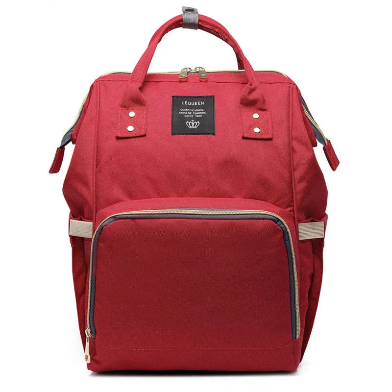 Stylish maternity diaper bag in various colors, featuring a paper bag design, separate bottle compartment, and discreet breastfeeding button.