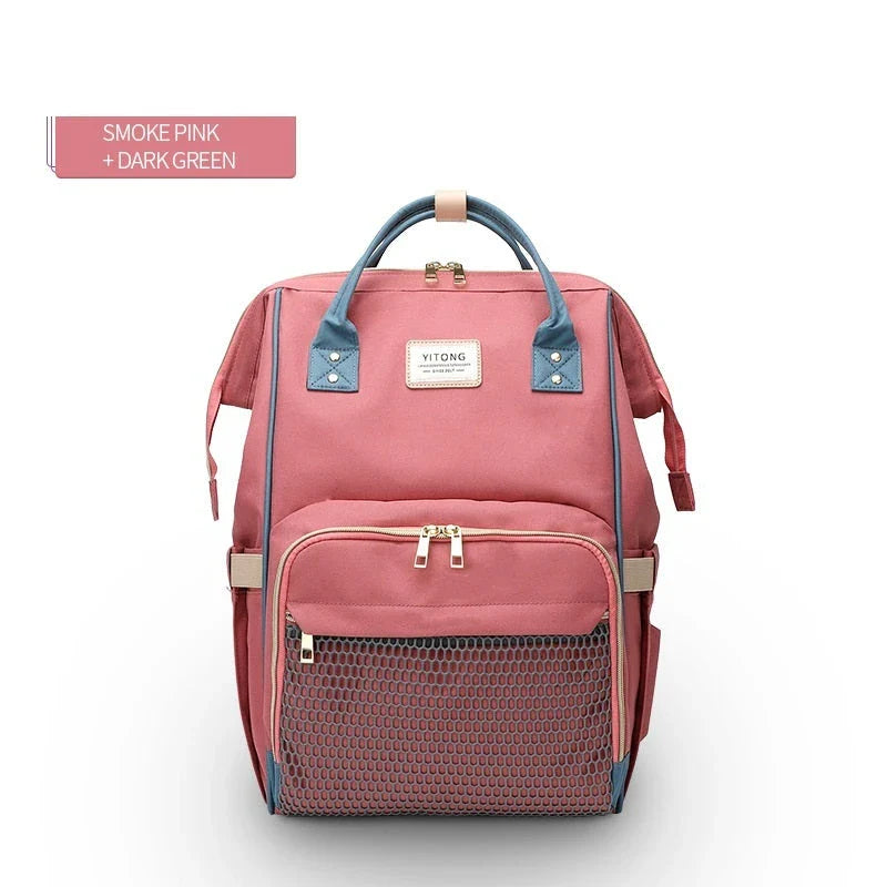 Stylish maternity diaper bag in various colors, featuring a paper bag design, separate bottle compartment, and discreet breastfeeding button.