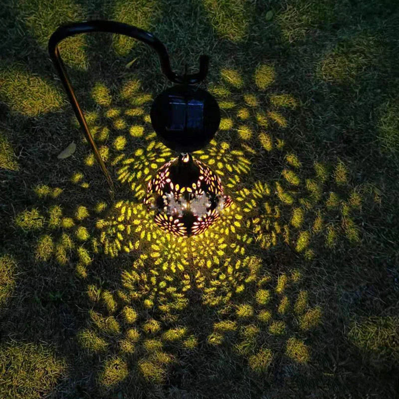 Elegant solar-powered garden lantern with a drop-shaped metal design and a soft, flower-patterned glow