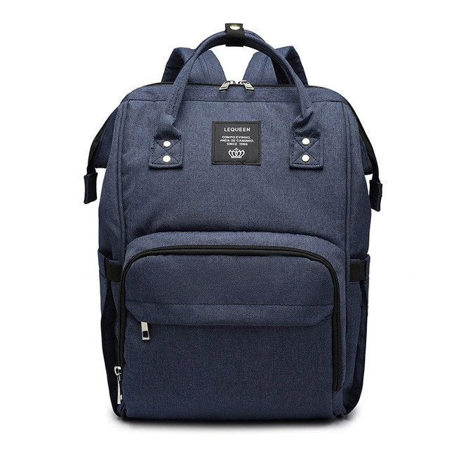 Stylish maternity diaper bag in various colors, featuring a paper bag design, separate bottle compartment, and discreet breastfeeding button.