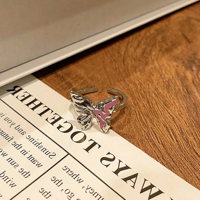 Copper butterfly women's ring with an open loop design on a plain background.
