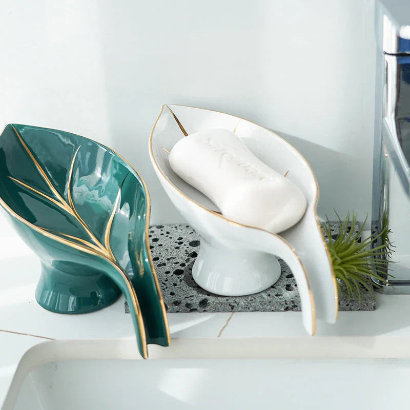 A ceramic soap dish with a sleek leaf-shaped design, featuring a suction cup base for secure and tidy placement in the bathroom or kitchen.