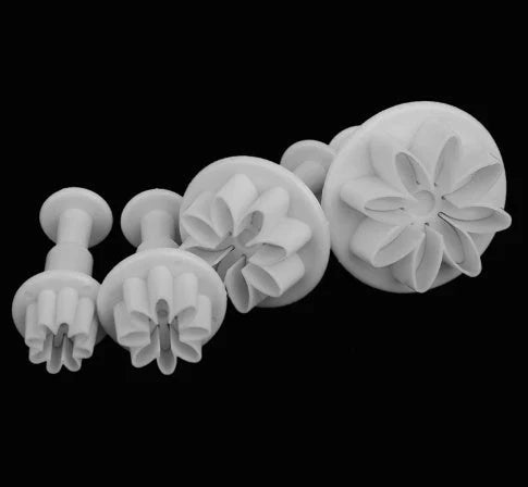 Assortment of cake decorating tools including plungers and knives in various floral designs
