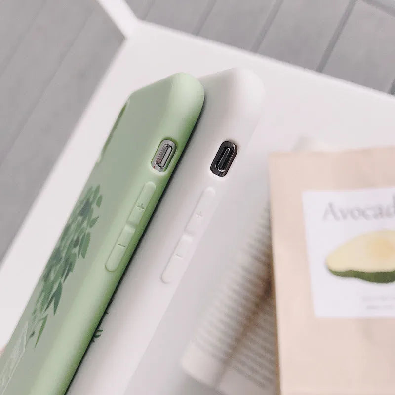 White silicone iPhone case with a painted green leaf plant design on the back.