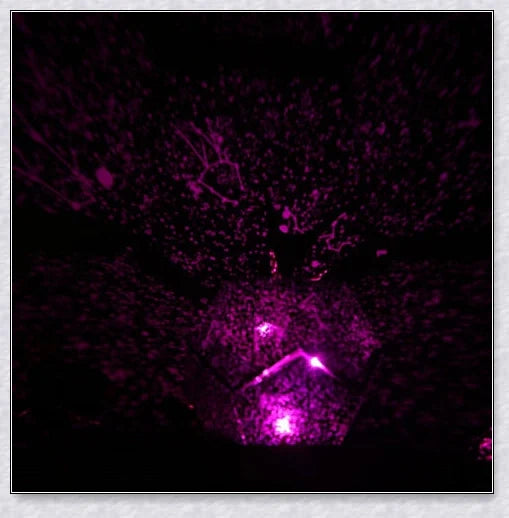 Enchanting star projector lamp casting a mesmerising galaxy display on the walls and ceiling of a bedroom