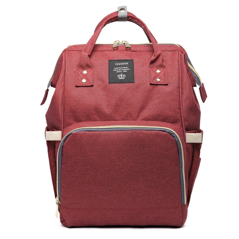 Stylish maternity diaper bag in various colors, featuring a paper bag design, separate bottle compartment, and discreet breastfeeding button.