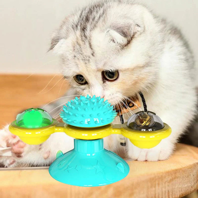 Cat playing with rotating windmill toy featuring luminous balls and suction base