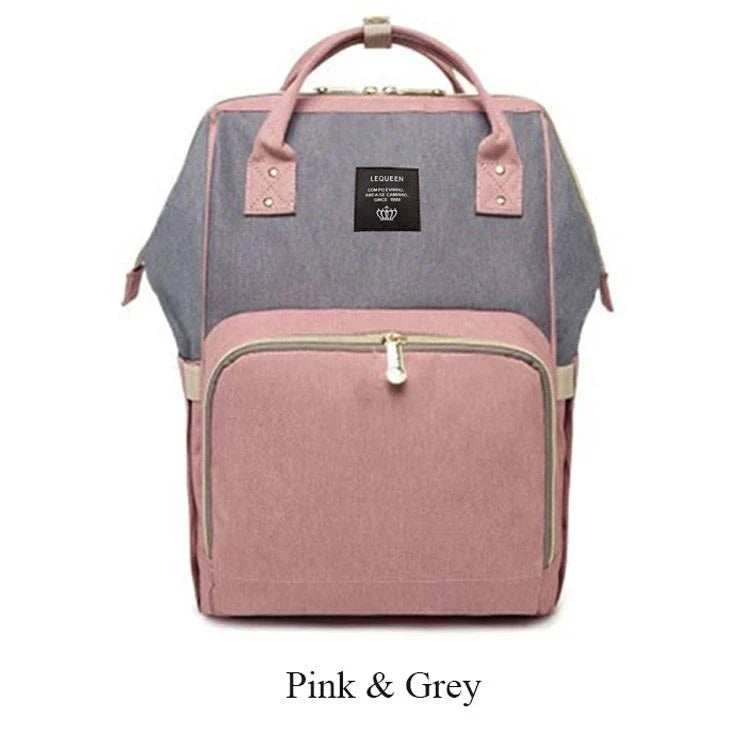 Stylish maternity diaper bag in various colors, featuring a paper bag design, separate bottle compartment, and discreet breastfeeding button.