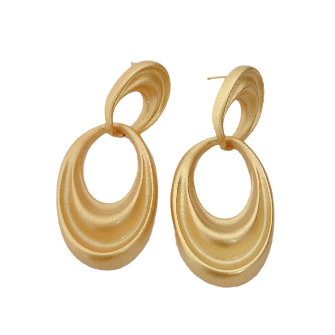 A pair of gold-coloured U-shaped women's earrings with a double circle design on a plain background.
