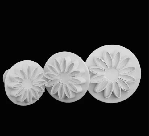 Assortment of cake decorating tools including plungers and knives in various floral designs