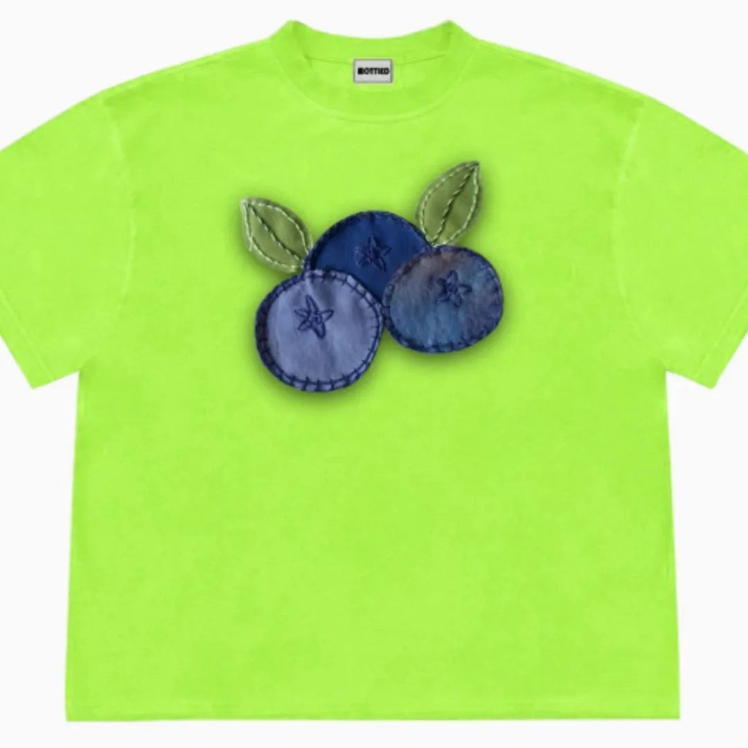A loose-fit blueberry patchwork short-sleeve T-shirt on a hanger, showing plant and flower designs.