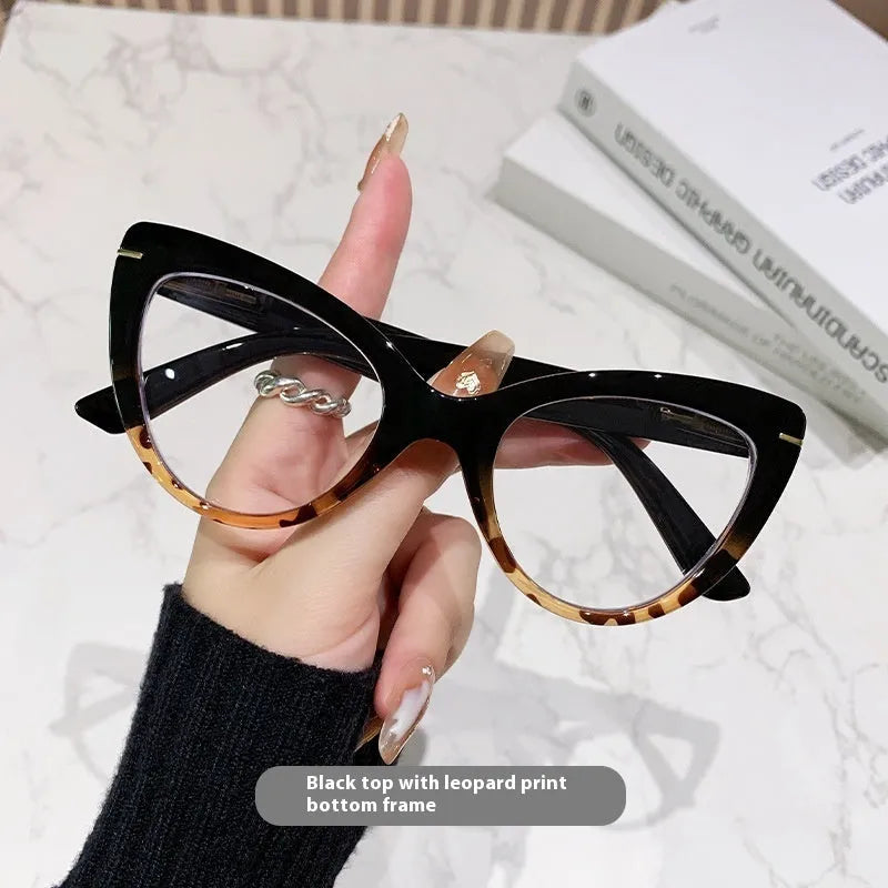Women's black floral cat's eye reading glasses with large frames on a wooden table.