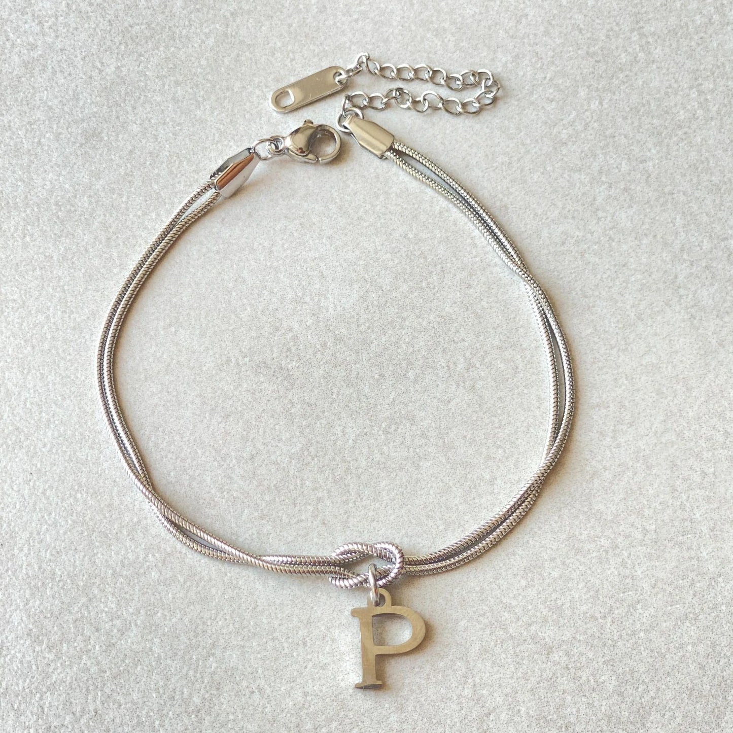 Elegant letter charm bracelets for women in gold and silver tones, featuring a delicate snake chain design and personalised letter charms.