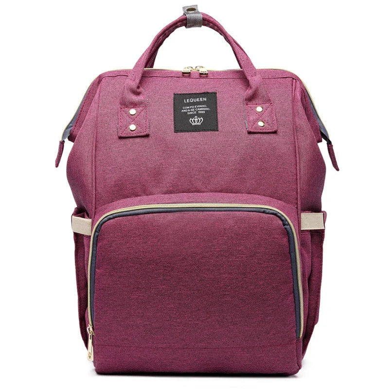 Stylish maternity diaper bag in various colors, featuring a paper bag design, separate bottle compartment, and discreet breastfeeding button.