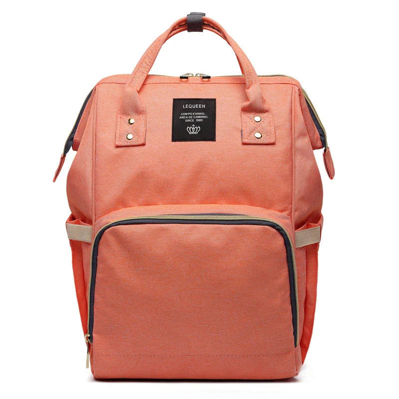 Stylish maternity diaper bag in various colors, featuring a paper bag design, separate bottle compartment, and discreet breastfeeding button.