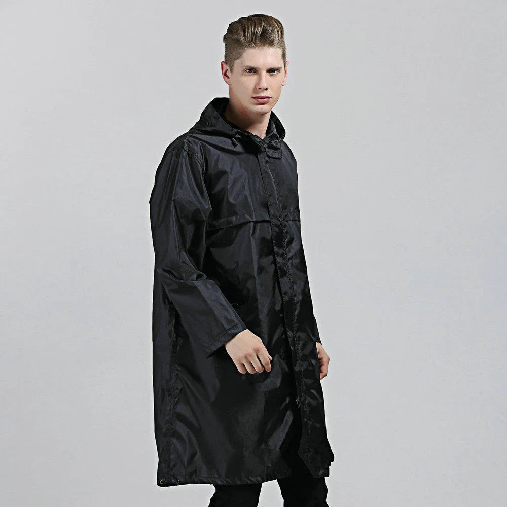 A man wearing a navy blue waterproof nylon raincoat standing in a field