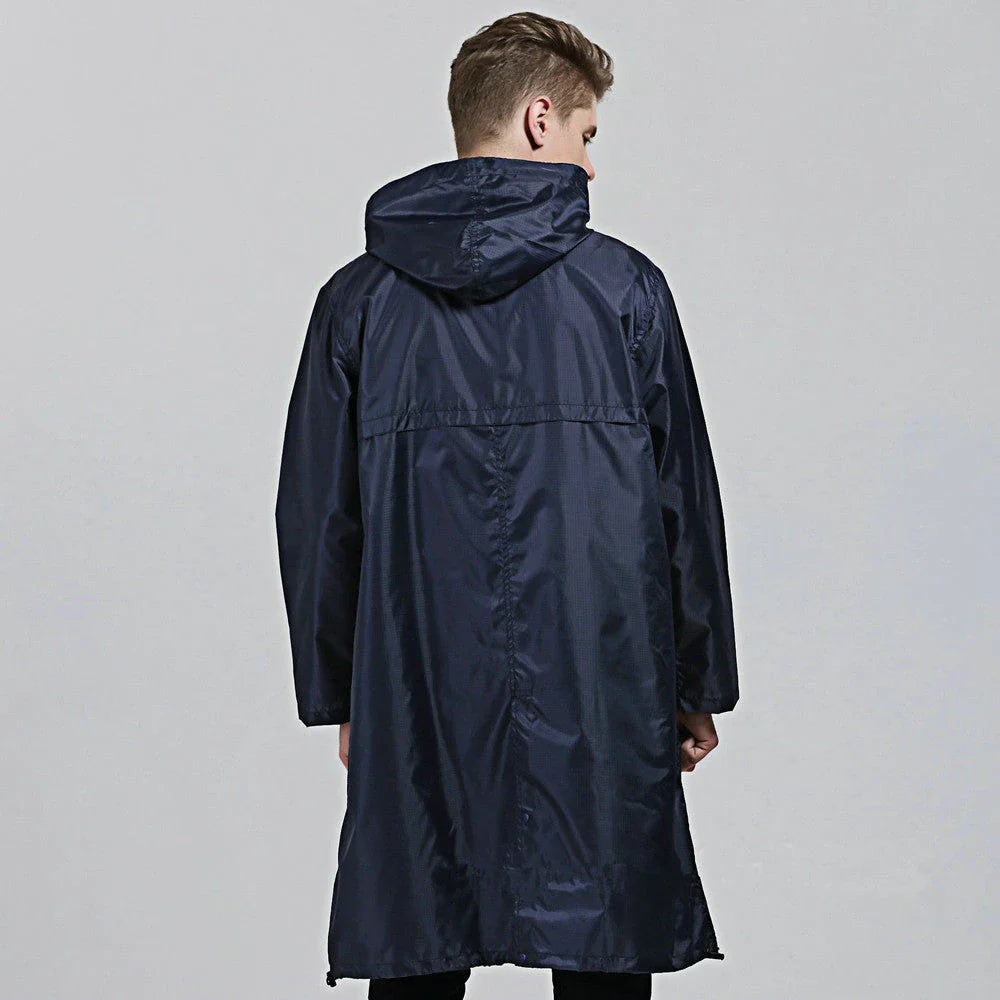A man wearing a navy blue waterproof nylon raincoat standing in a field