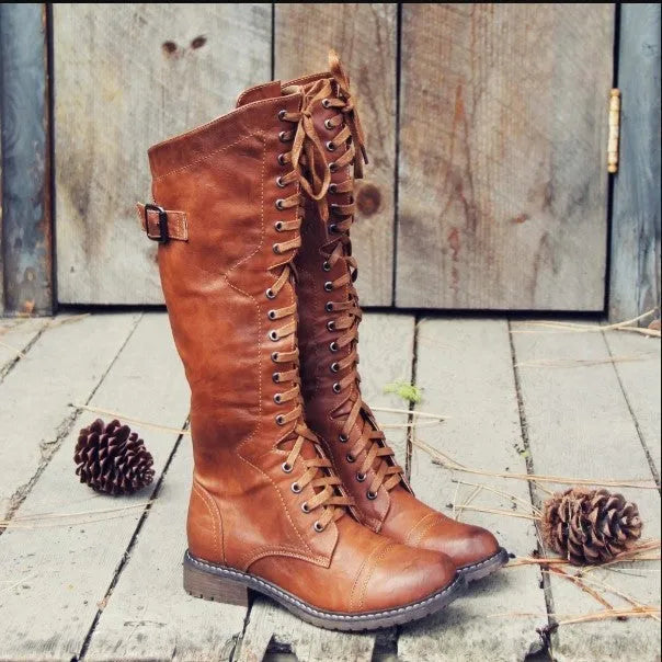 Women's black knight ankle boots with cross straps and buckles over lace-up front.