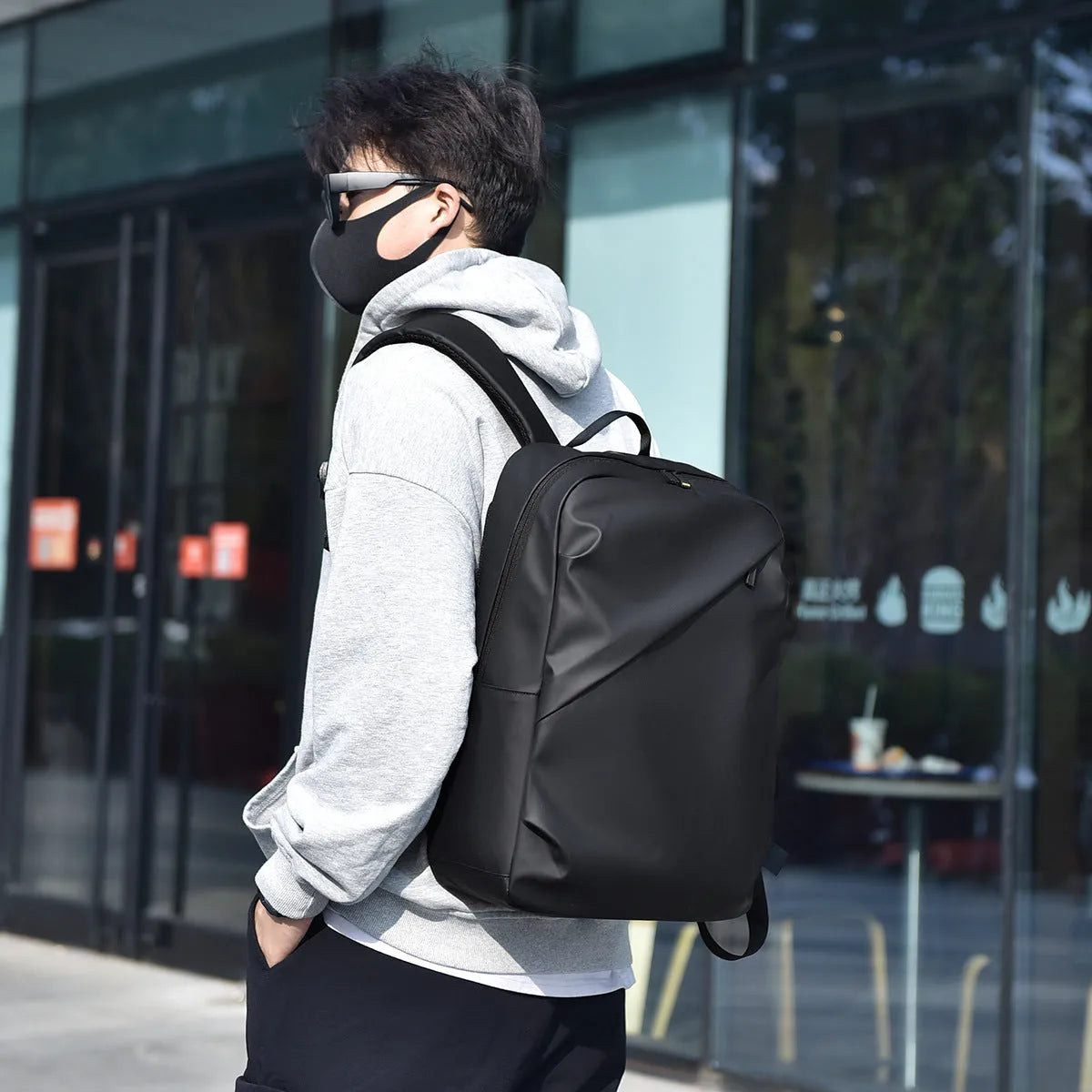Large black waterproof PU leather laptop backpack with sewing thread details on a simple design.