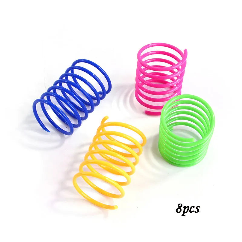 Assortment of colourful plastic coil spring toys for cats on a plain surface.