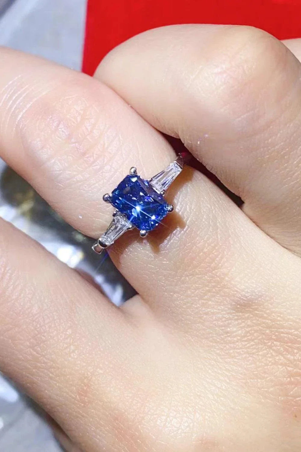 A shimmering 1 carat moissanite ring in a platinum-plated setting with a rectangular shape and sparkling accent stones