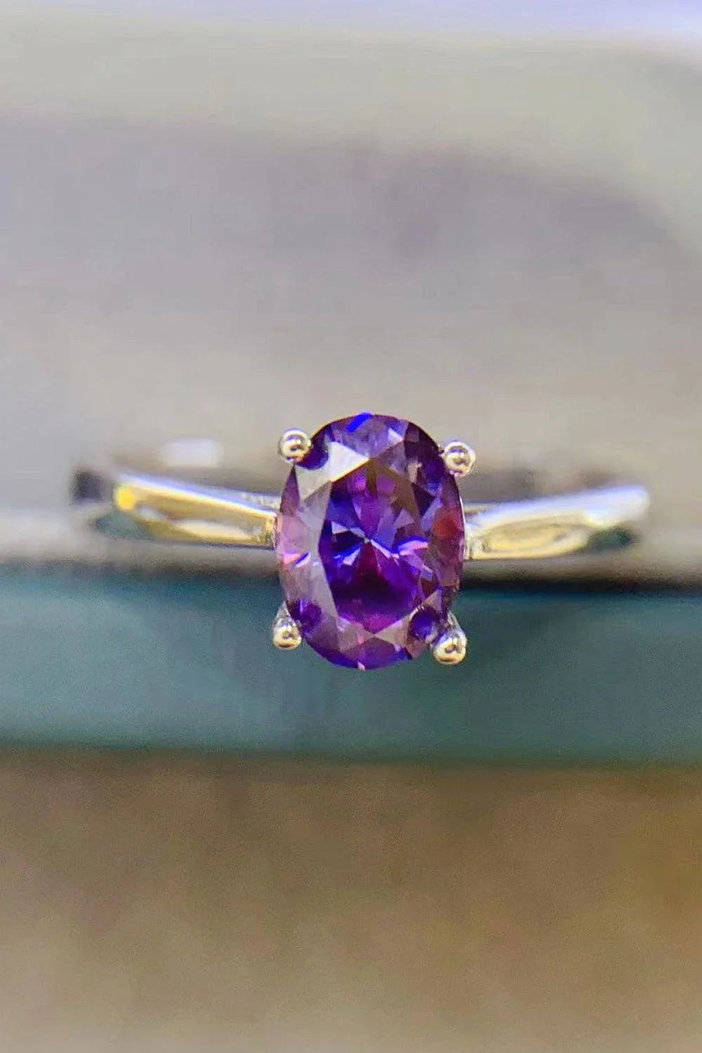 A sparkling 1 carat moissanite stone set in a 925 sterling silver 4-prong solitaire ring with a platinum-plated finish.