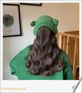 A cosy and stylish woollen hat featuring a charming cartoon frog design with big, expressive eyes