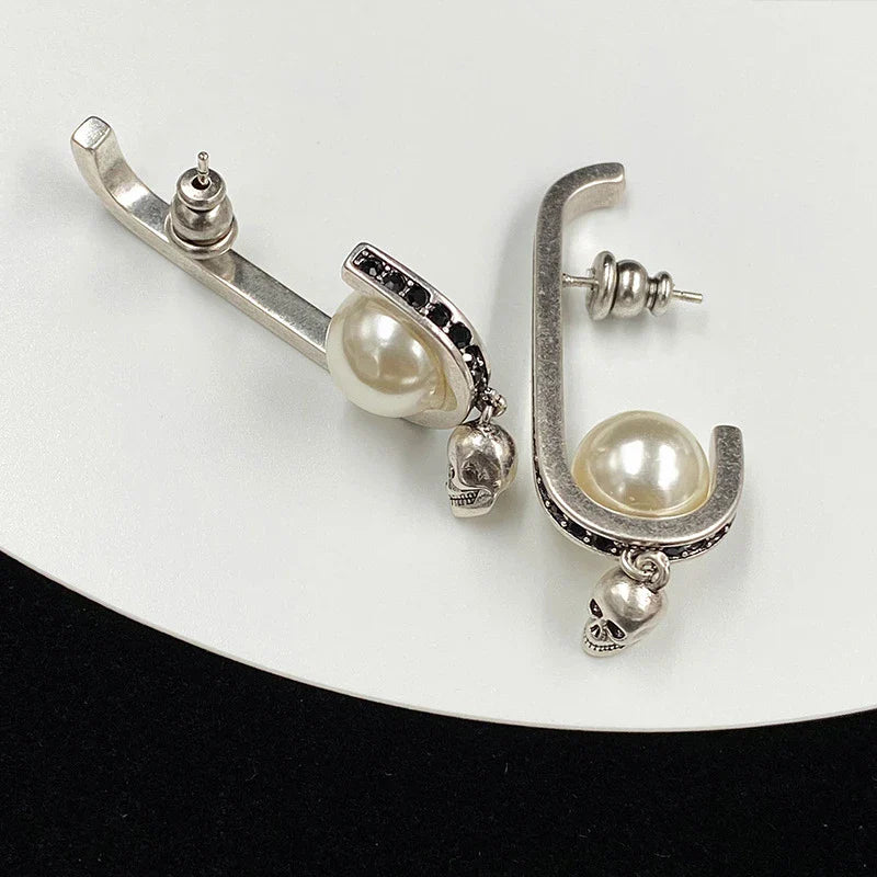 Pair of gold-tone earrings with a skull-shaped design, featuring pearls and diamonds