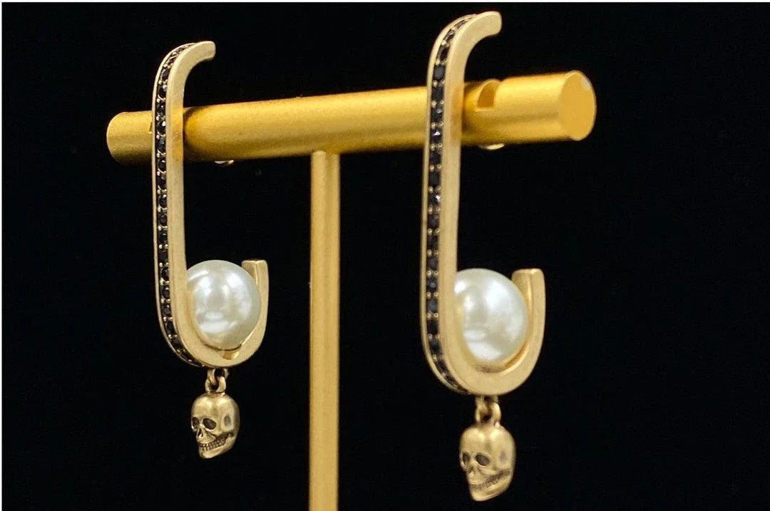 Pair of gold-tone earrings with a skull-shaped design, featuring pearls and diamonds