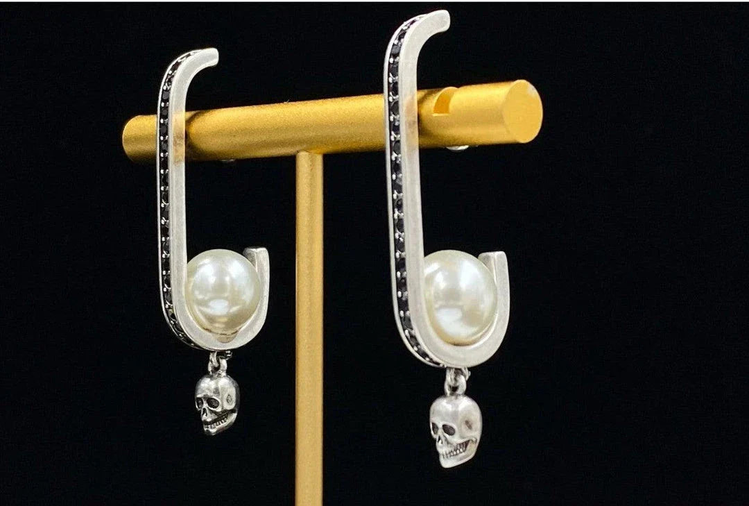 Pair of gold-tone earrings with a skull-shaped design, featuring pearls and diamonds
