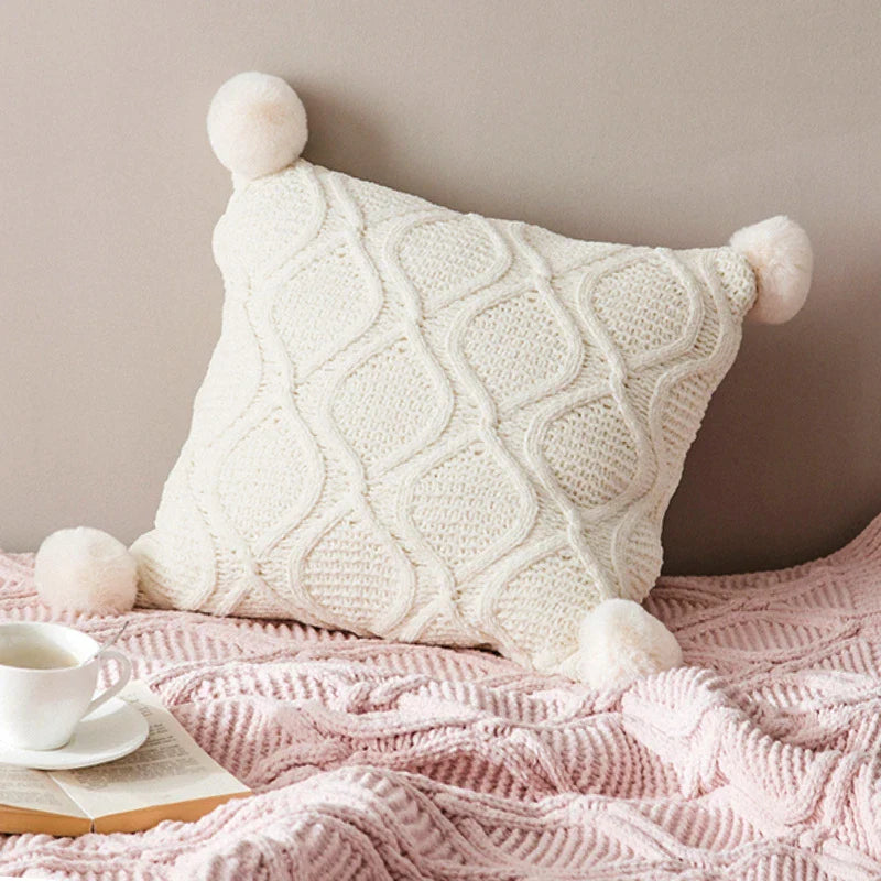 A cosy, knitted Nordic-inspired wind ball pillow in a neutral white colour, perfect for adding a touch of Scandinavian style to your living room decor.