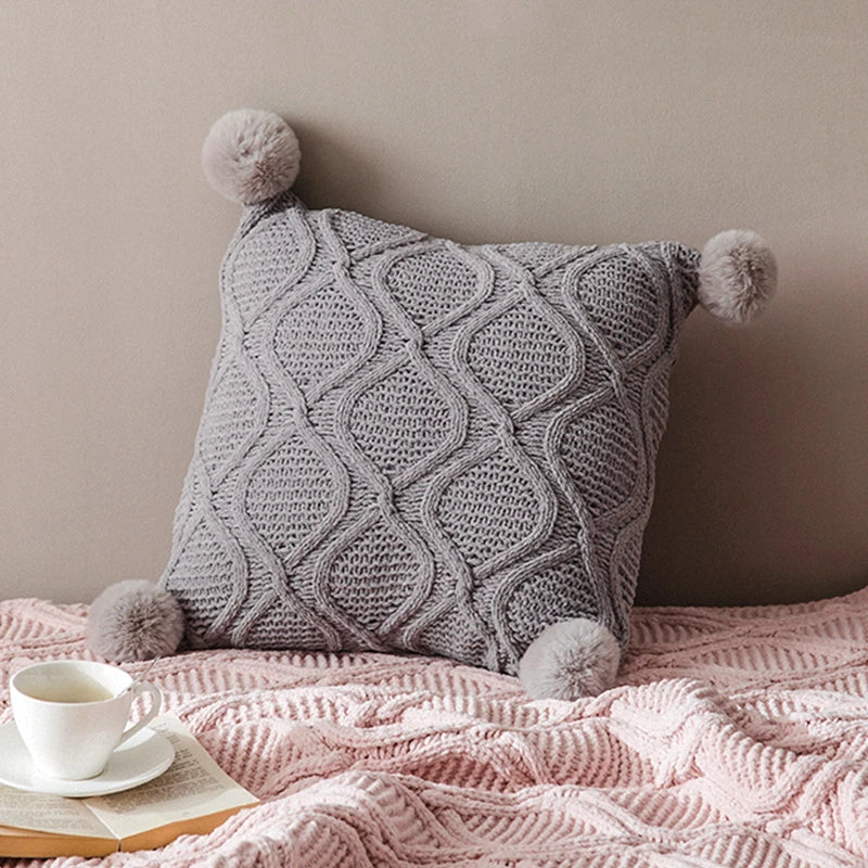 A cosy, knitted Nordic-inspired wind ball pillow in a neutral white colour, perfect for adding a touch of Scandinavian style to your living room decor.
