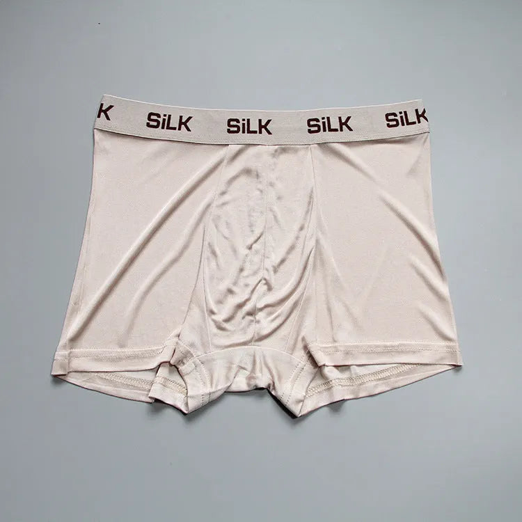 Man wearing loose-fit mid-waist shorts in navy blue silk fabric.