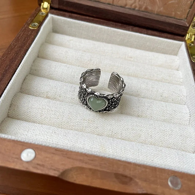 Retro style wide silver heart shape ring with adjustable band on a wooden surface