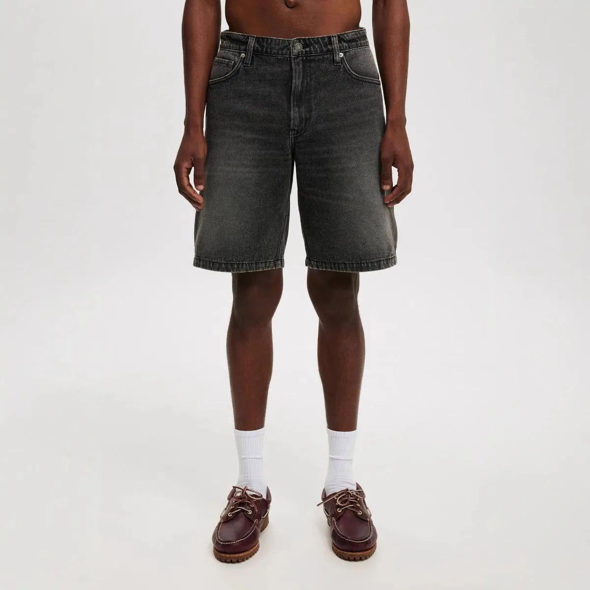 Men's light blue loose straight-leg cotton jeans laid flat, showing the front design and fifth-pants length.