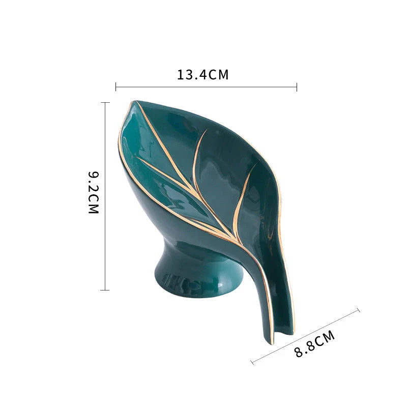 A ceramic soap dish with a sleek leaf-shaped design, featuring a suction cup base for secure and tidy placement in the bathroom or kitchen.