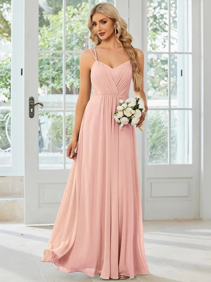 Woman wearing a light green sleeveless dress with a long pleated A-line skirt.