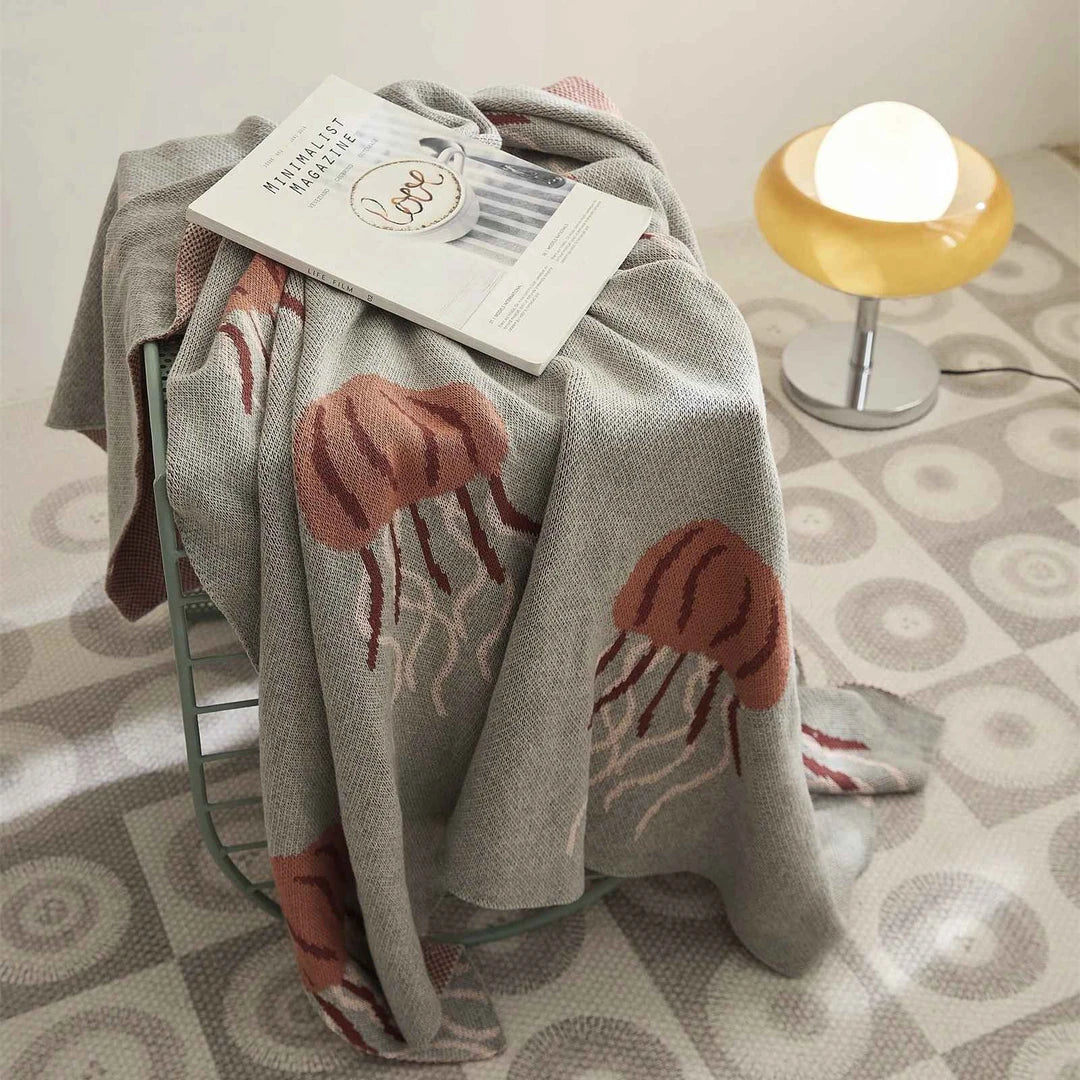 Cosy jellyfish-patterned cotton knit throw blanket in green and grey colours, showcasing its soft, plush texture and unique design.