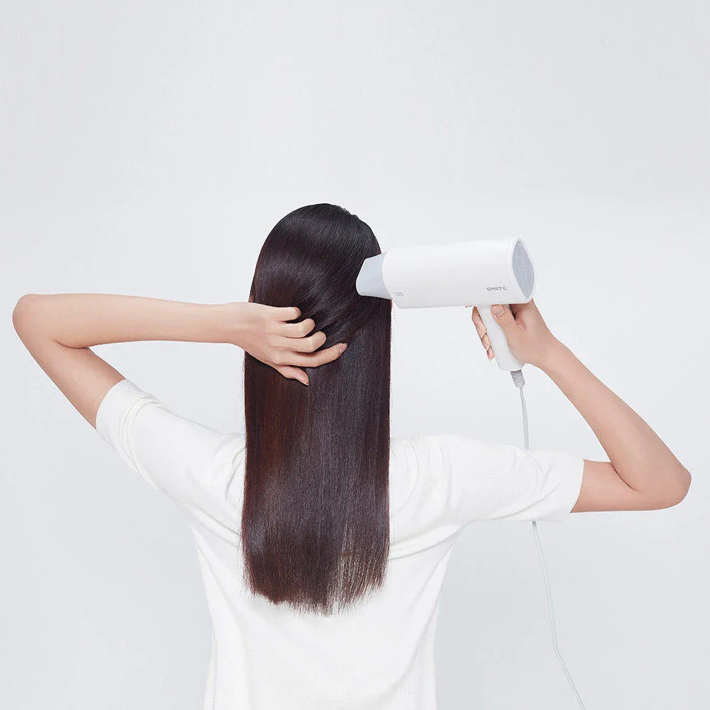 Compact and portable hair dryer with foldable handle, two-speed settings, and multiple nozzle positions for versatile styling