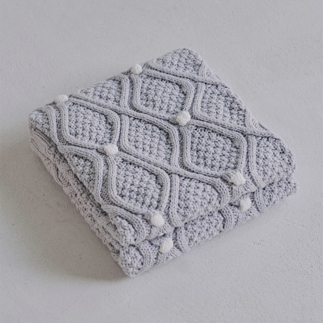 Cosy chunky knit blanket with charming pompoms in multiple sizes and colours for elegant home décor
