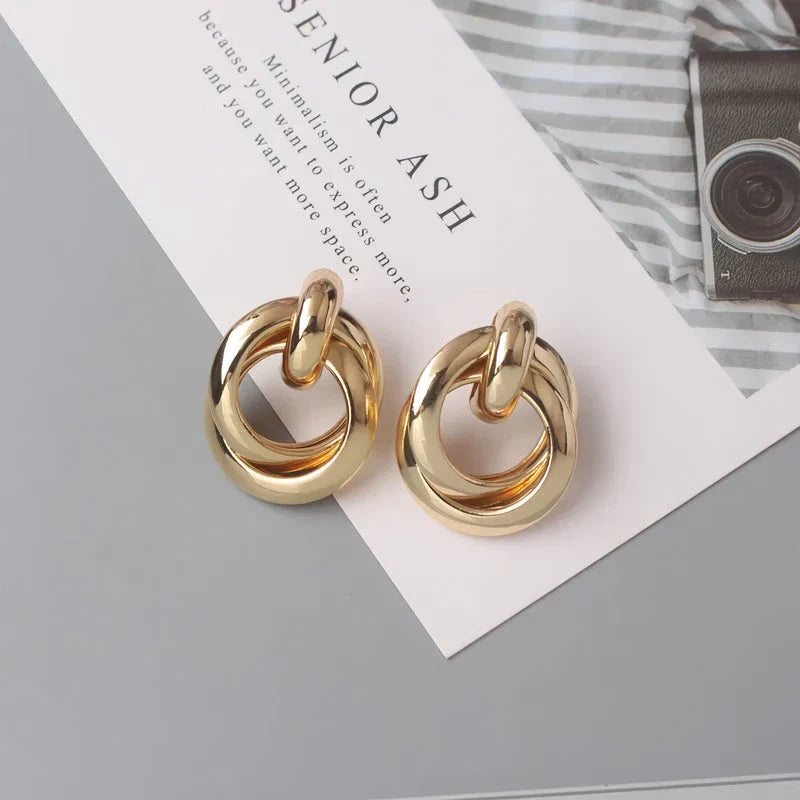 Elegant geometric statement earrings with a luxurious gold finish, featuring a unique hollow twist design.