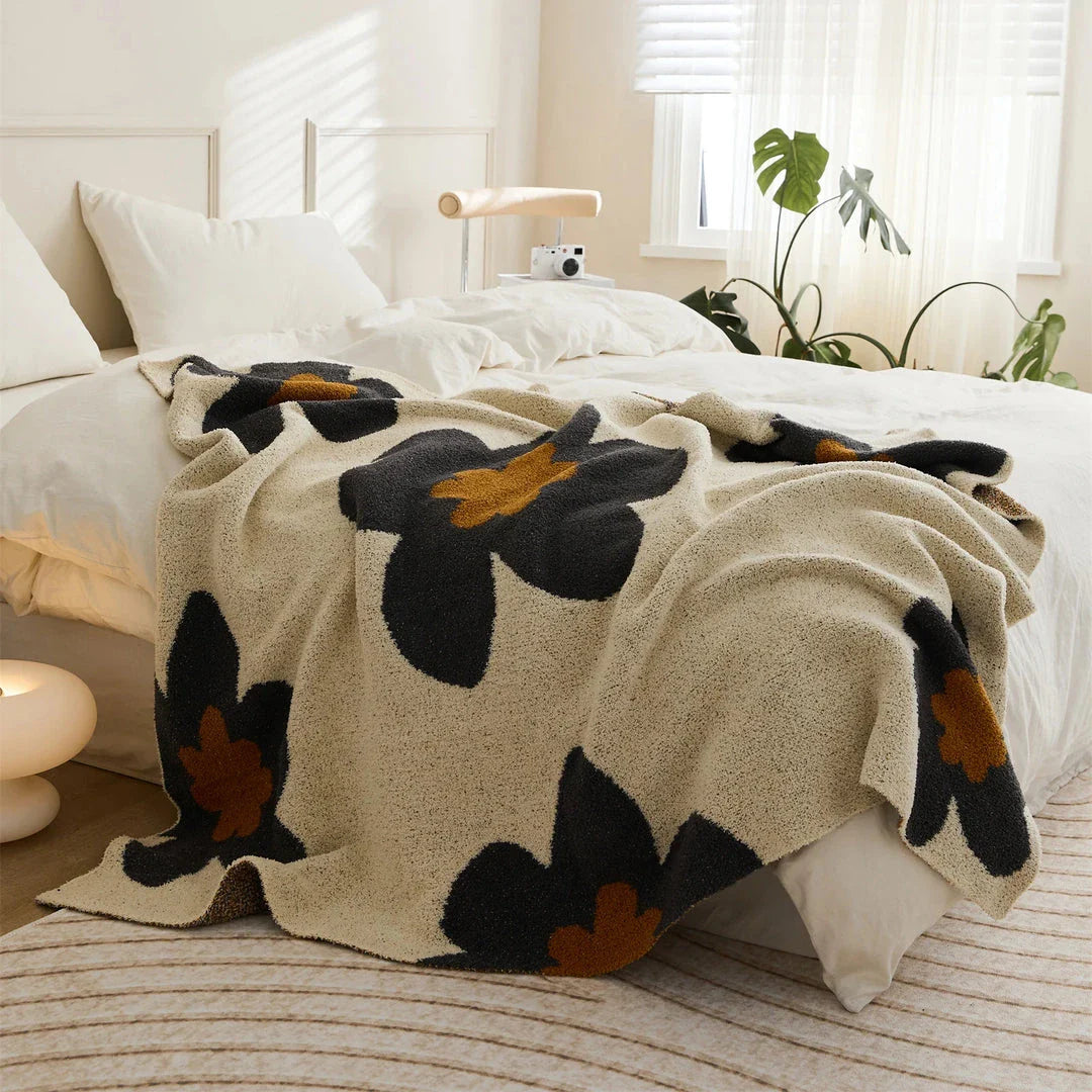 Cosy floral knitted throw blanket in red, grey, and orange shades - a high-quality microfibre accessory for year-round comfort and style
