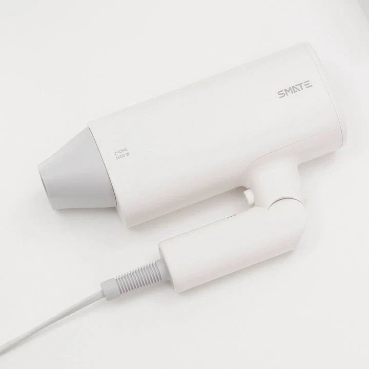 Compact and portable hair dryer with foldable handle, two-speed settings, and multiple nozzle positions for versatile styling