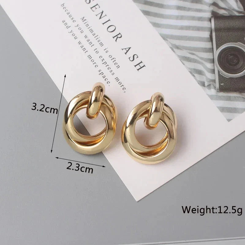 Elegant geometric statement earrings with a luxurious gold finish, featuring a unique hollow twist design.