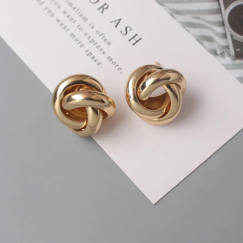 Elegant geometric statement earrings with a luxurious gold finish, featuring a unique hollow twist design.