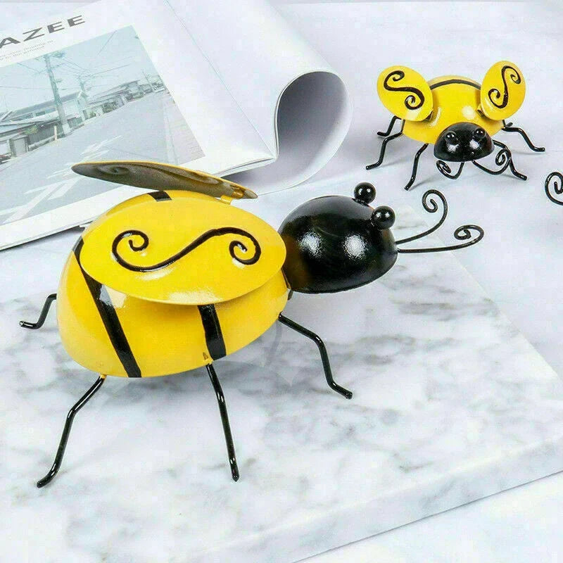 Four decorative metal bumble bee sculptures in a natural garden setting